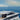 Motor yacht at sea with a Starlink dish on a Scanstrut APT-150-SL-01 tower on the hardtop, coastline behind